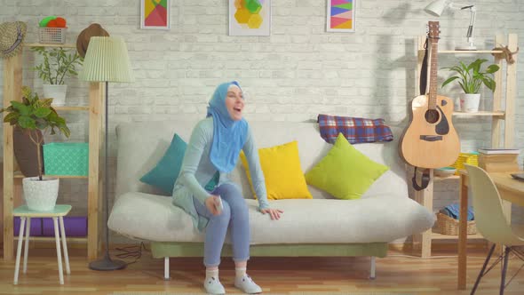 Pretty Muslim Woman in a Hijab Learns About Winning Using a Smartphone and Dances