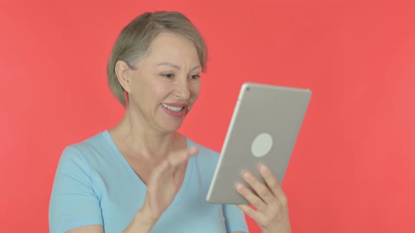 Video Call on Tablet By Old Woman on Red Background