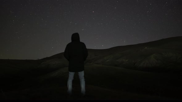 A Man Stands Against the Background of the Night Sky with Stars