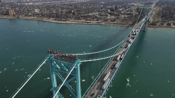 Ambassador bridge over Detroit river with long line of semi-trucks passing USA - Canada border. Aeri