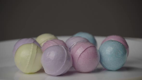 Bath Bombs in Different Colors Spin Against a Black Background