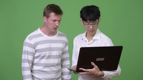 Two Sad Young Multi-ethnic Businessmen Using Laptop While Getting Bad News Together