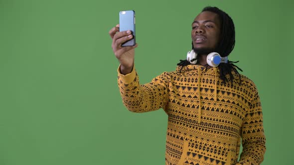 Young Handsome African Man with Dreadlocks Against Green Background