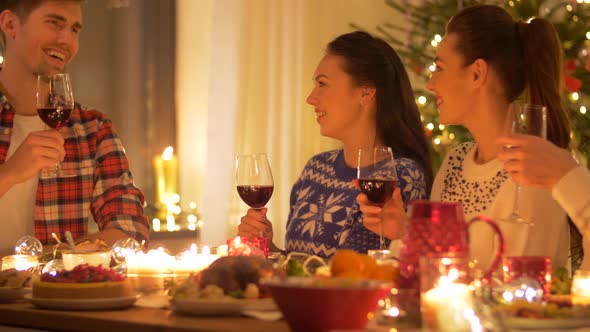 Happy Friends Drinking Red Wine at Christmas