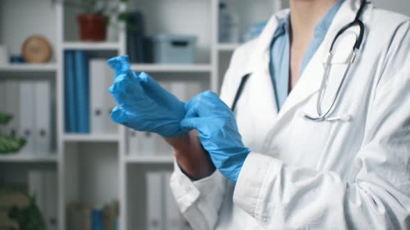 The Doctor Puts On Gloves Close Up. A Medic Stands In A Medical Office Wearing Blue Latex Gloves