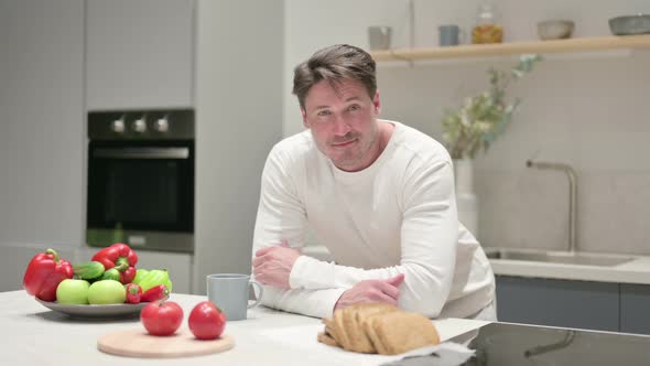 Content Middle Aged Man Looking at the Camera in Kitchen