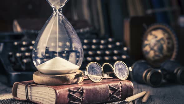 Moving sand in an hourglass, old diary and binocular, retro style