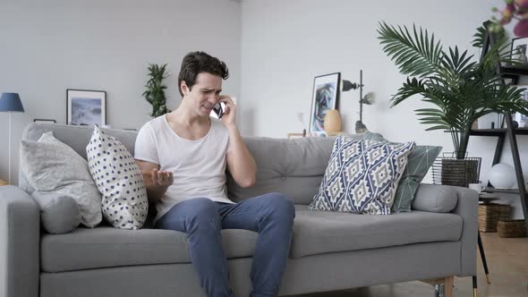 Angry Screaming Man Talking on Phone, Sitting on Sofa