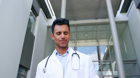 Doctor holding digital tablet while walking in corridor