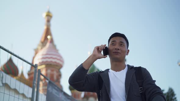 Real Time Portrait Shot of a Young Asian Guy Talking on the Phone in the Center of Moscow.