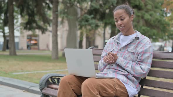 African Woman Talking on Video Call While Sitting Outdoor on Bench