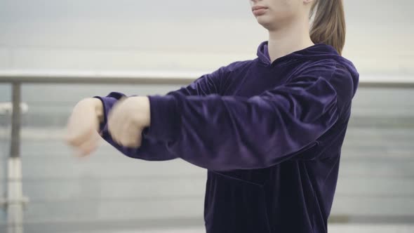 Unrecognizable Sportswoman Stretching Wrists Outdoors