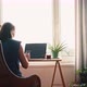 A Woman Working on a Laptop While Sitting at the Table Opposite a Window - VideoHive Item for Sale