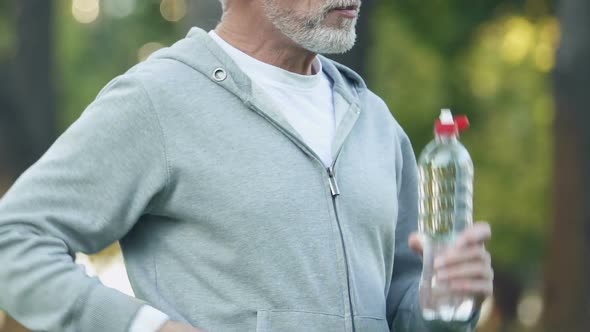 Smiling Man Drinking Bottled Beverage, Keeping Water Balance After Workout