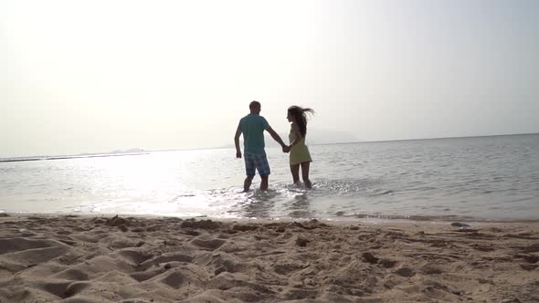 Romantic Couple Running on Beach at Sea Sunset Holding Hands