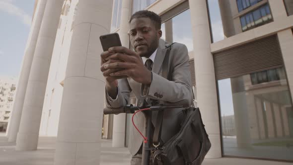 Businessman Using Phone and E Scooter in Downtown