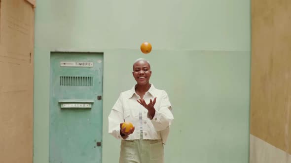 Slow motion shot of happy woman juggling with oranges outdoors