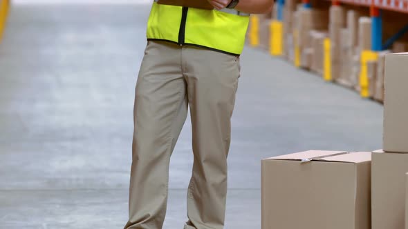 Male warehouse worker writing on clipboard