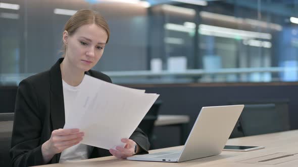 Businesswoman With Laptop Reading Documents at Work