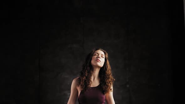 The Girl Shakes Her Head From Side To Side During Meditation. Young Girl in a Dark Room and