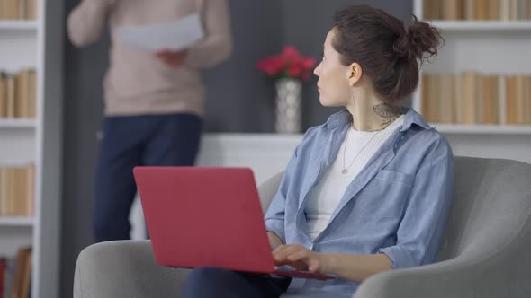 Busy Caucasian Young Woman Typing on Laptop Keyboard Working in Home Office Looking Back at