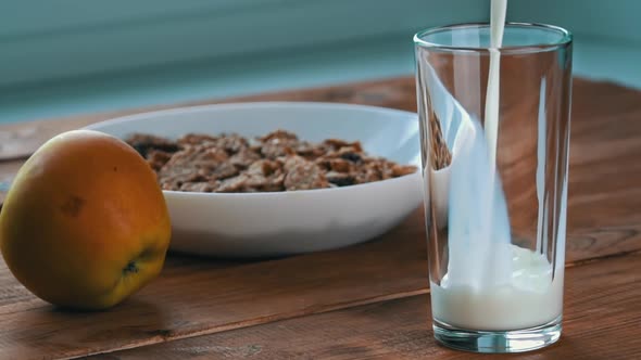 Pouring Milk Into a Glass for Breakfast with Oatmeal in Slow Mo