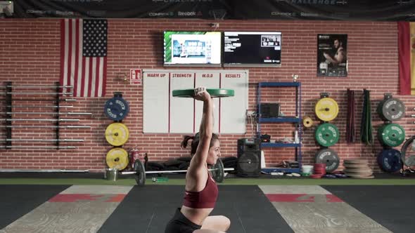 Strong Woman Using Weight Plate Over the Head to Squat in Slow Motion