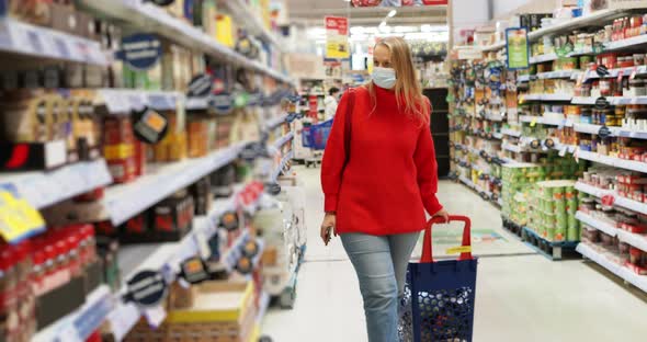 Woman Buyer with Full Trolley in the Supermarket