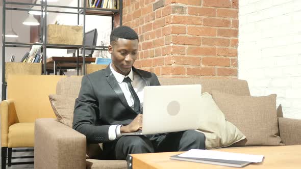 Black Businessman Cheering Success, Working on Laptop