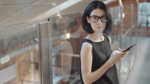 Elegant Businesswoman Using Smartphone and Posing for Camera in Office