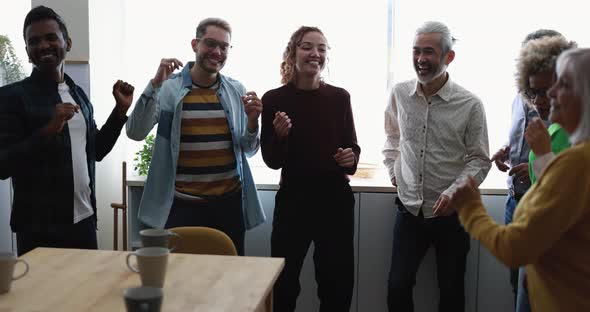 Multiracial happy friends having fun dancing at home kitchen