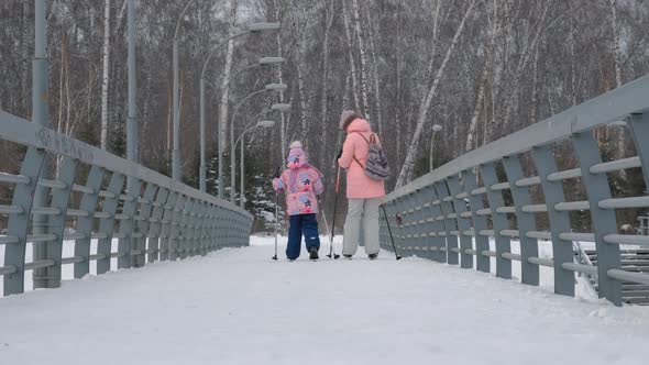 Mother with Daughter CrossCountry Skiing in Park