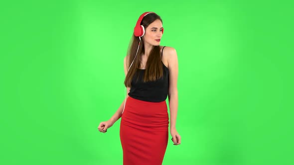 Cheerful Girl Dancing and Enjoys Music in Big Red Headphones. Green Screen