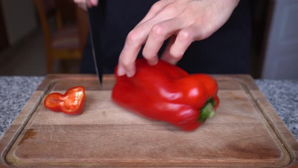 Close-up of a man cutting a red bell pepper and opening it