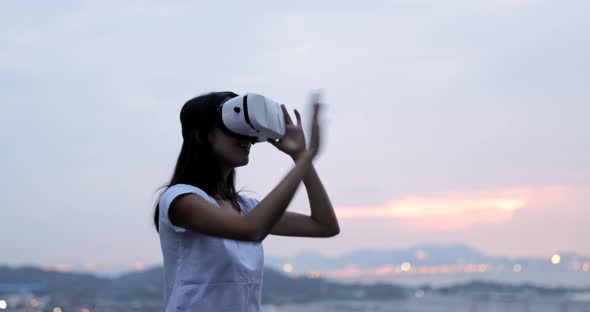 Woman looking at the VR device in the sunset time 