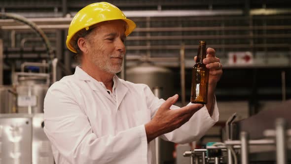 Factory worker inspecting a glass bottle at bottling plant