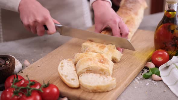 Woman Slicing Baguette on Wooden Cutting Board at Domestic Kitchen