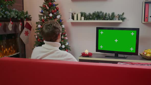 Man wearing a sweater is watching Green Chroma Key Screen TV