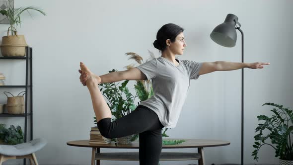 Young attractive multi ethnical woman wearing sportswear, pants and top, doing stretching yoga