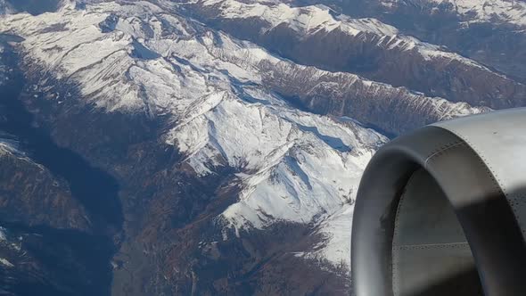 Close Up Of Airplane Turbine Viewed Through The Window With Snowy Mountain Peaks In Background. POV