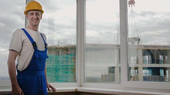 Smiling builder in the already built house. Construction site.