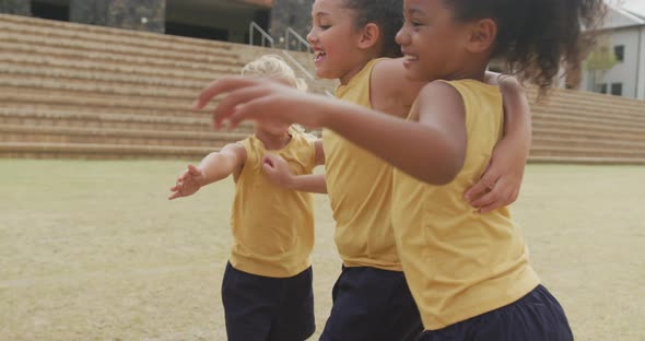 Video of legs of diverse girls hugging after soccer match in front of school