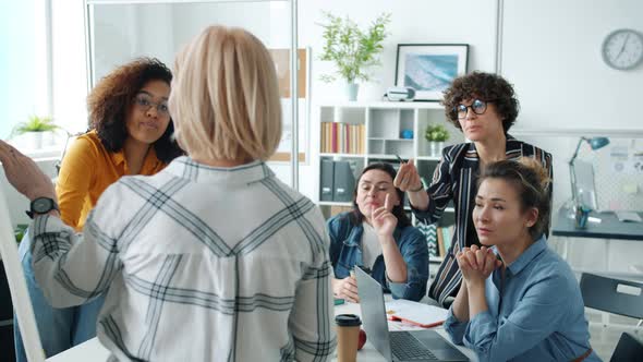 Creative Team of Employees Talking To Woman Making Presentation in Glass Wall Office