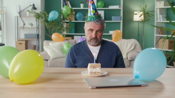 A Depressed Man in a Party Cap Celebrates His Birthday Alone at Home