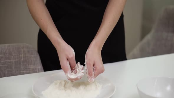 Unrecognizable Woman Takes a Handful of Flour From a Plate Lets It Fall Fray Through