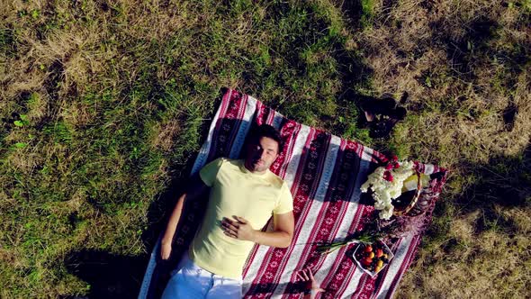 Aerial Top View A Young Couple in Love with Young People Lying on a Green Lawn and Kissing. The Girl