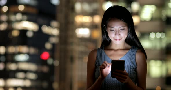 Woman using smart phone in Hong Kong city at night 