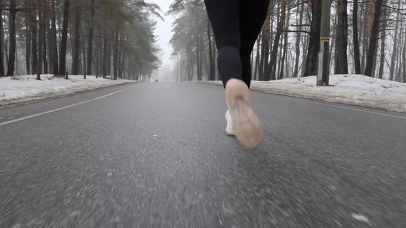 Legs of Sportive Attractive Caucasian Girl Running in The Snowy Park in Winter as A Part of Training