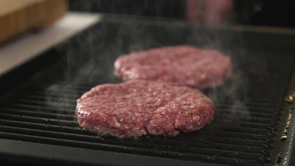 Raw beef patty cooked in hot pan. Fast food in restaurant.