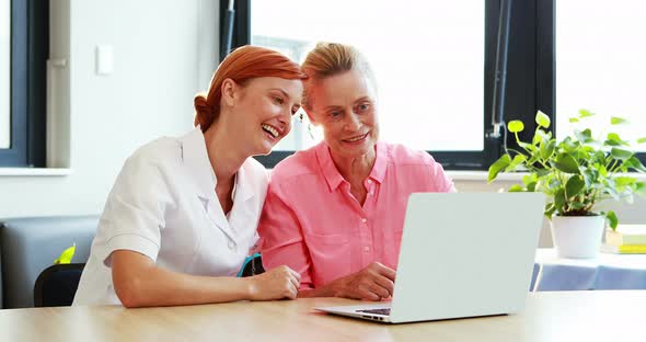 Portrait of nurse and a senior patient using laptop